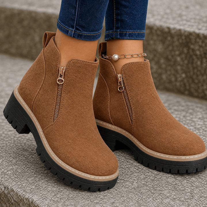 Brown suede platform ankle boots with gold side zips and lug soles, worn with blue jeans