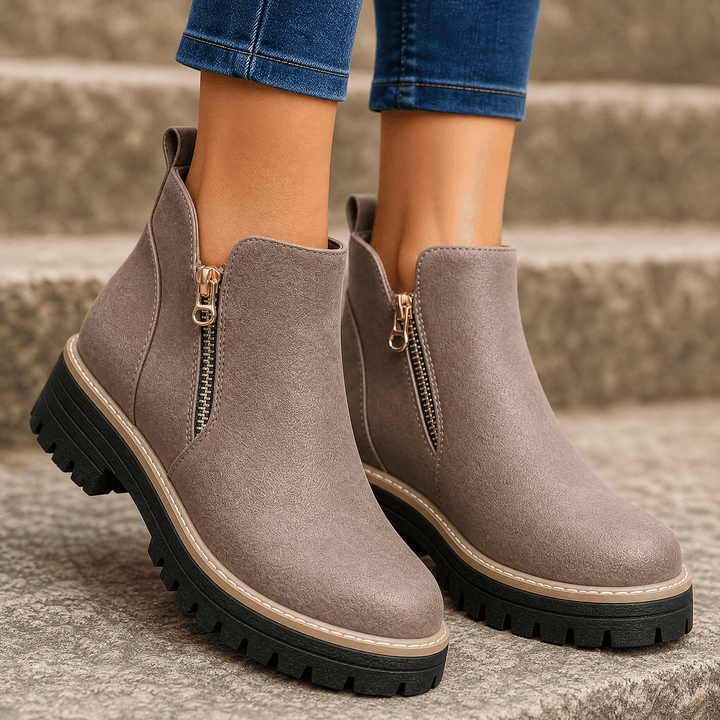 Taupe suede platform ankle boots with gold side zips and chunky lug soles, worn with jeans