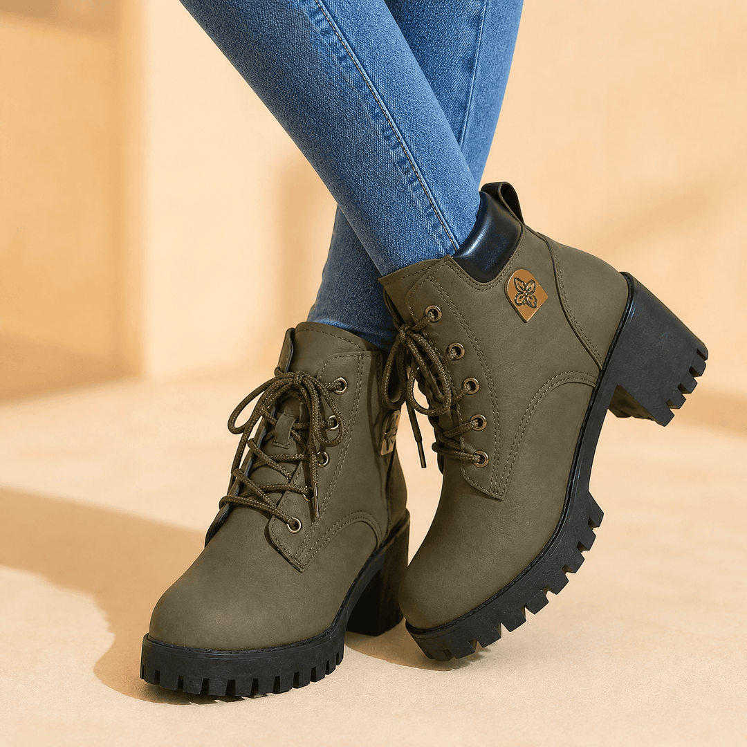 Olive green lace up platform boots with chunky lug soles, worn with blue jeans, angled view