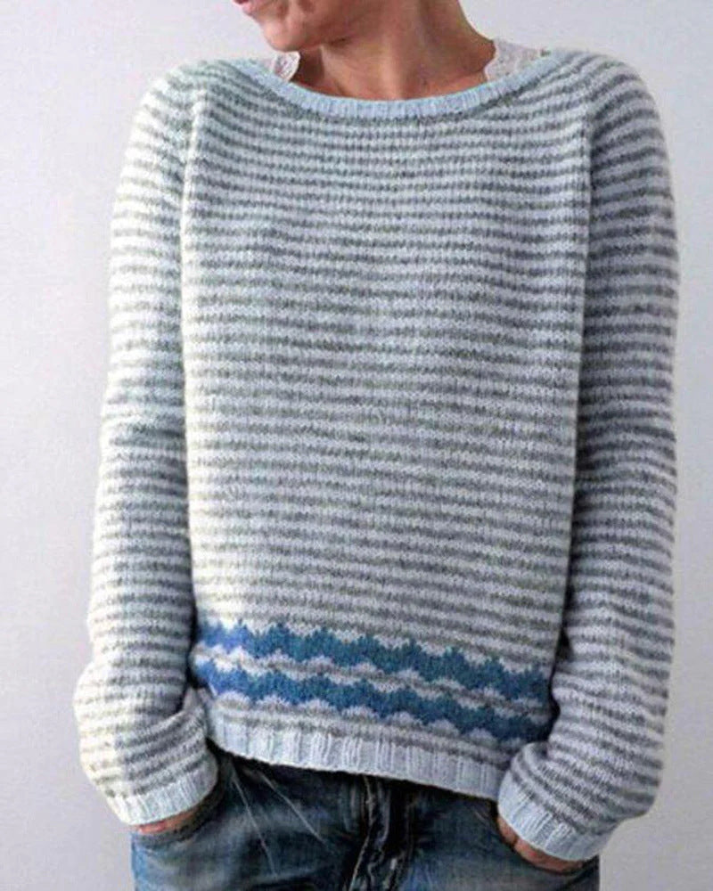 Pale striped knit sweater with a blue zigzag band above the ribbed hem
