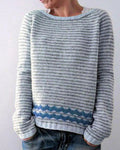 Pale striped knit sweater with a blue zigzag band above the ribbed hem