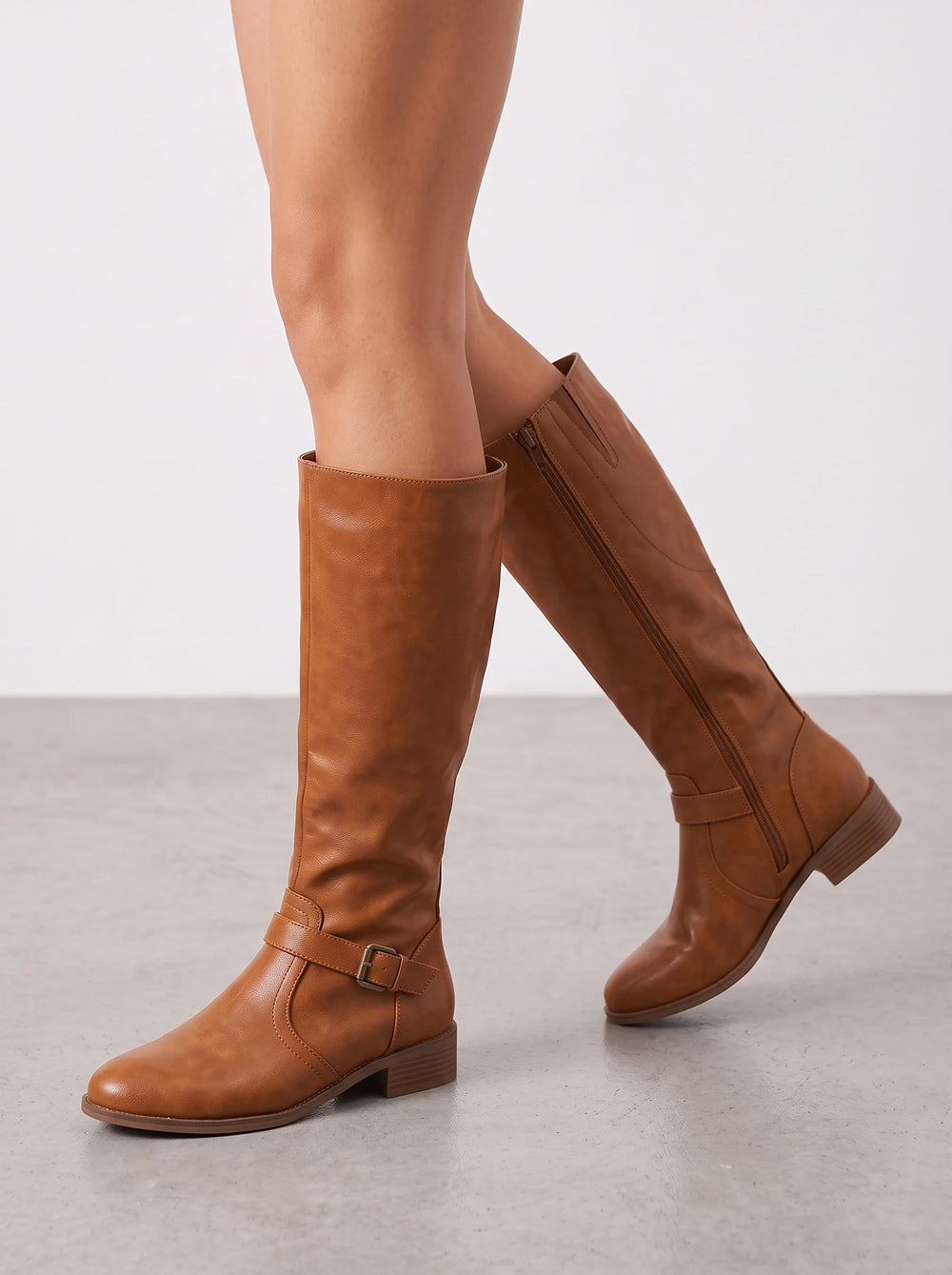Tan leather riding boots seen from the outer side while walking
