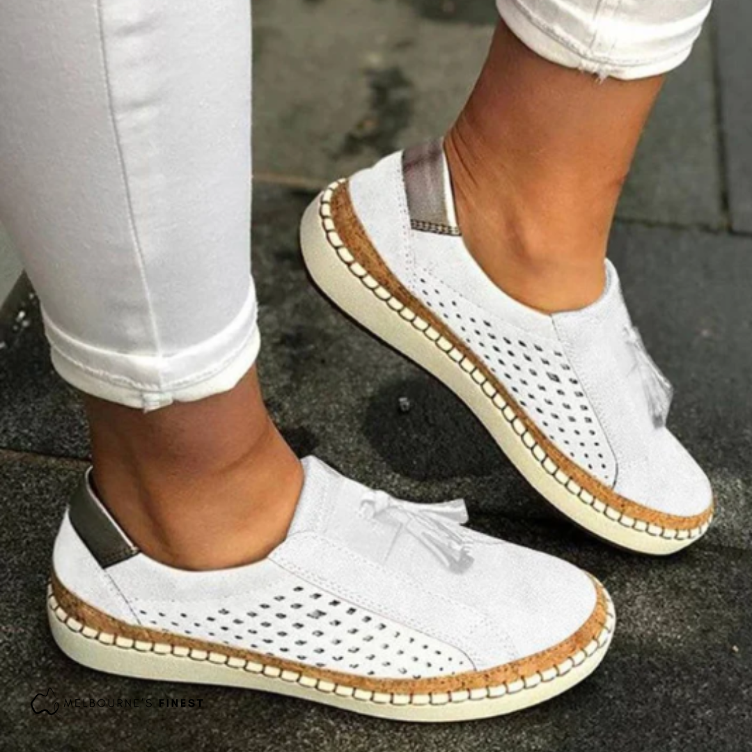 White slip on sneakers with perforated panels and a tassel