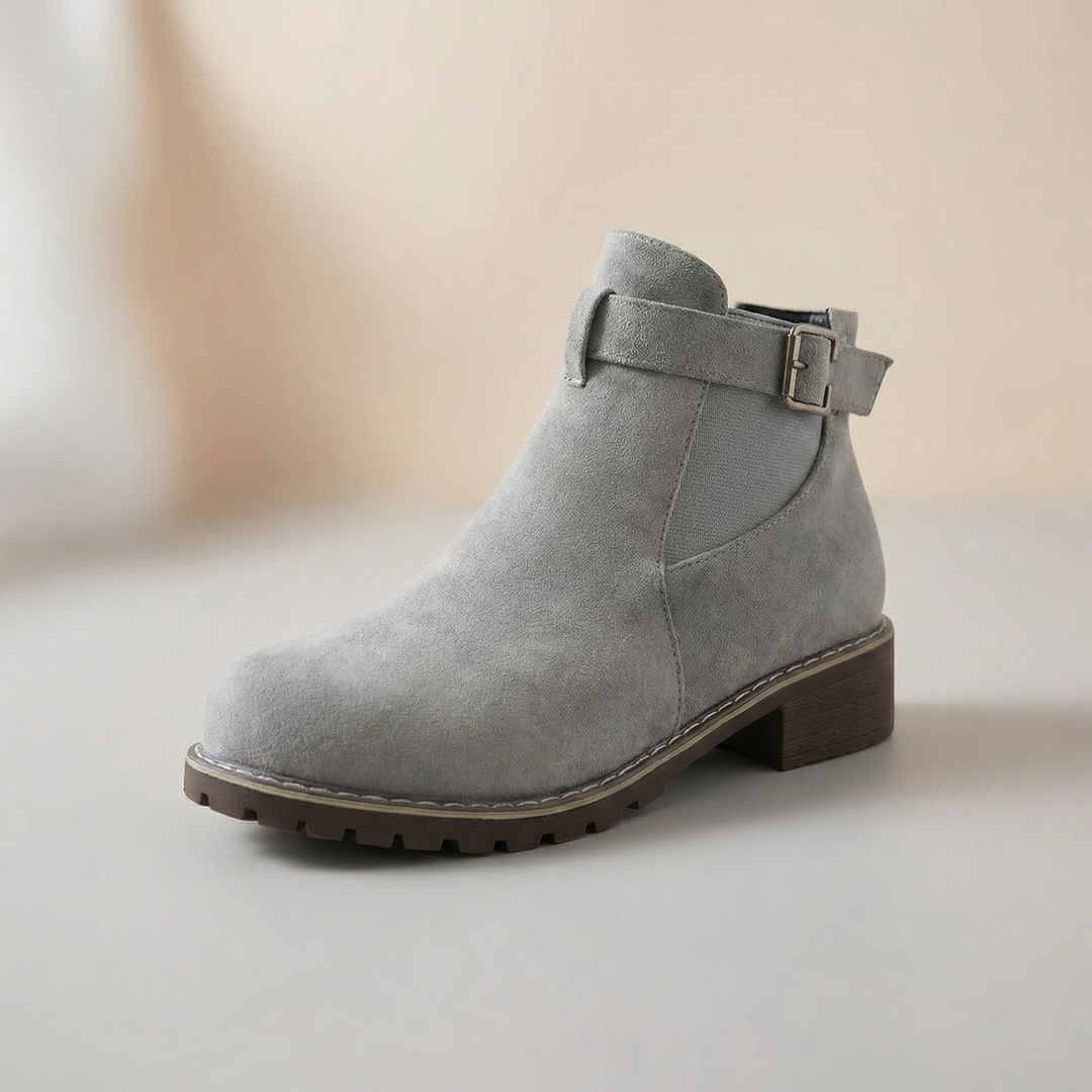 Grey suede ankle bootie with a buckle strap, side view