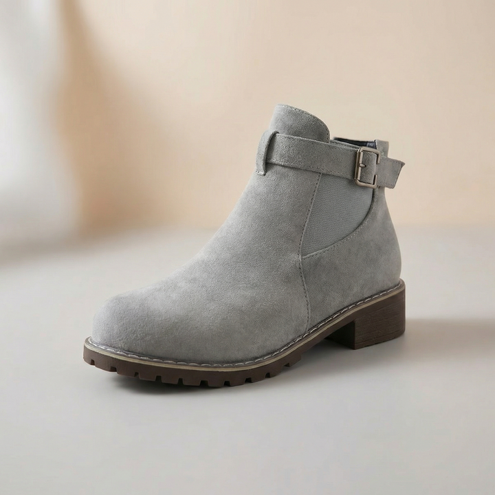 Grey suede ankle bootie with a buckle strap, side view