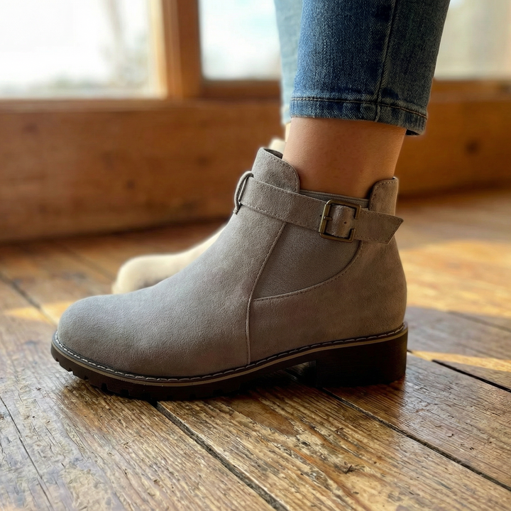 Grey buckle strap ankle booties worn with cuffed jeans