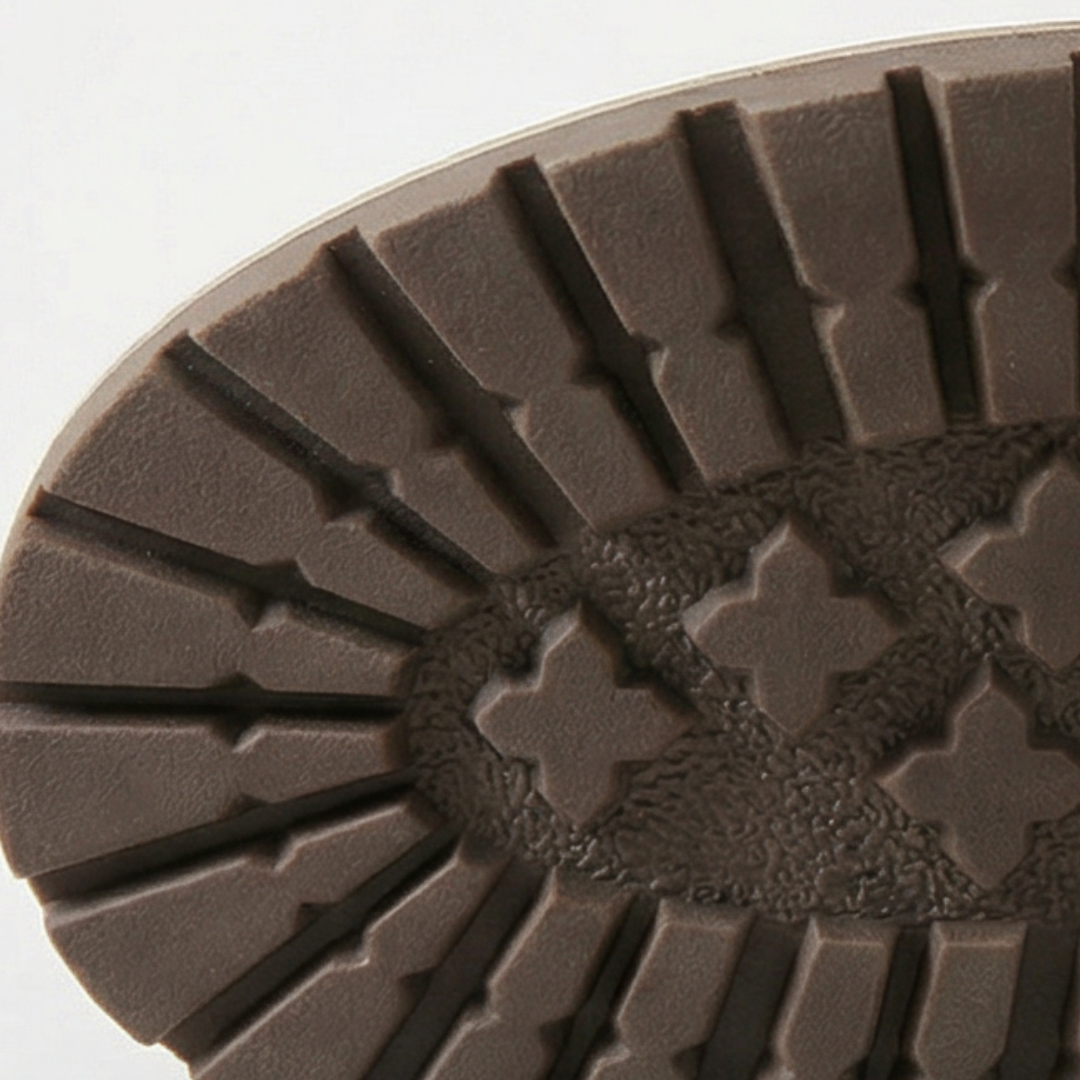 Stacked heel and treaded outsole of a grey ankle bootie