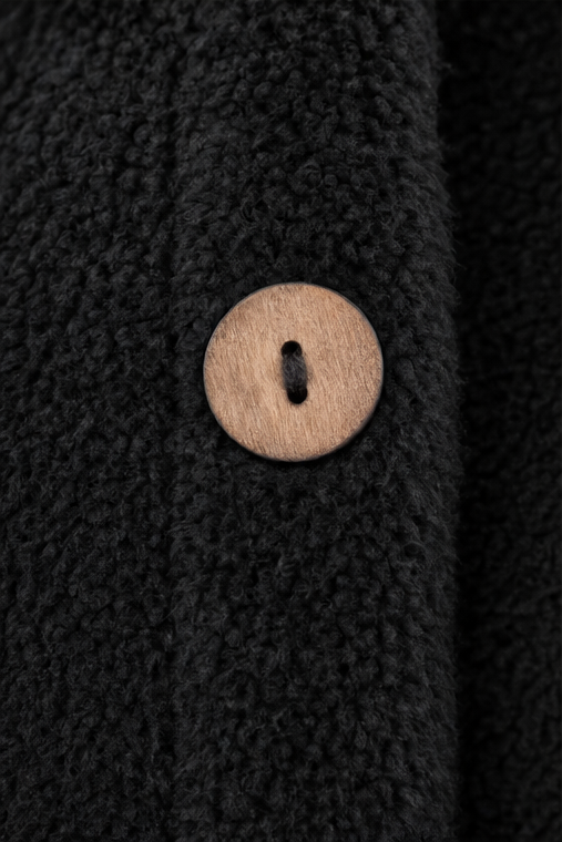 Close up of a wooden button on a black fleece shirt jacket