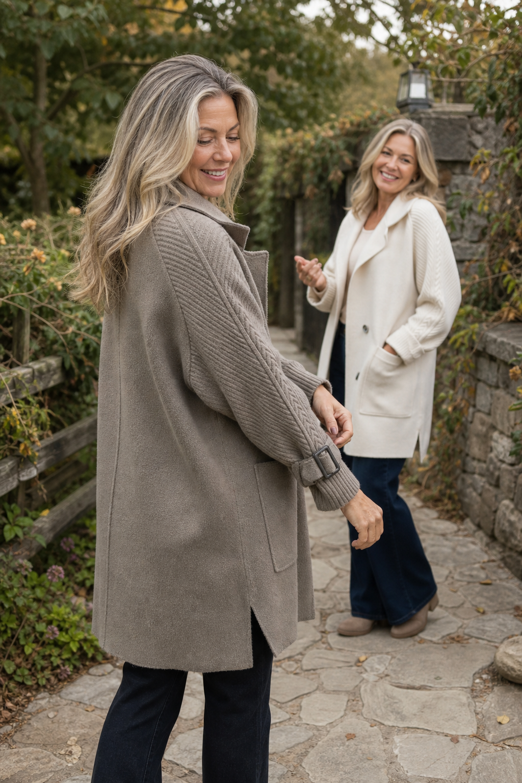 Two women outdoors in taupe and cream cable knit sleeve coats