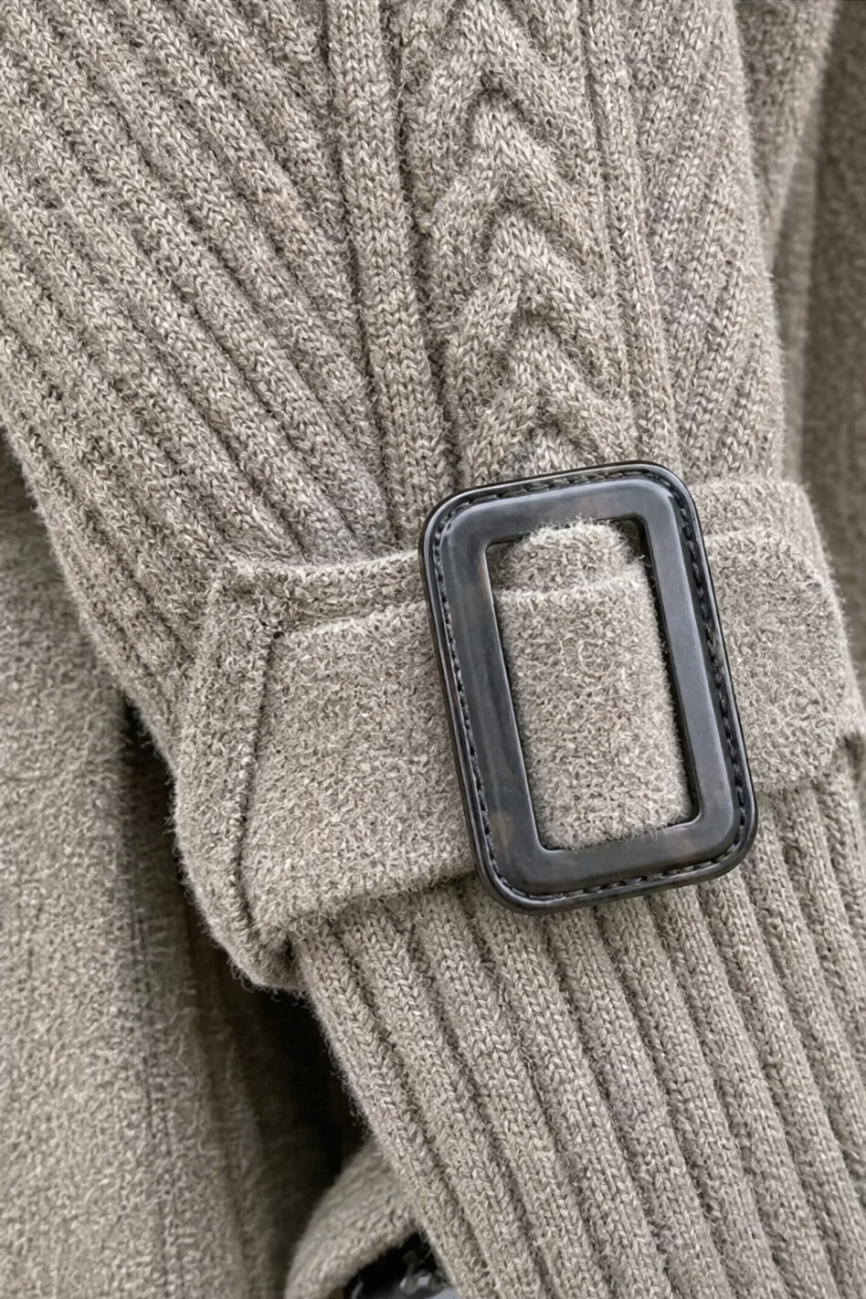 Buckle cuff detail on a cable knit coat sleeve
