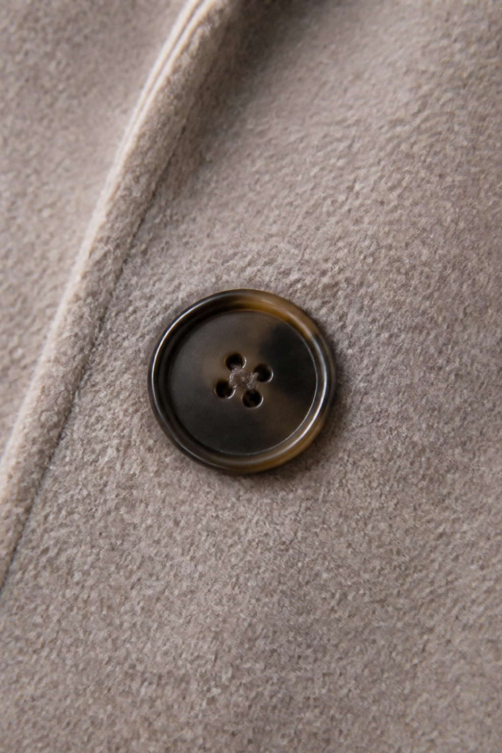 Close up of a horn button on a taupe wool blend coat