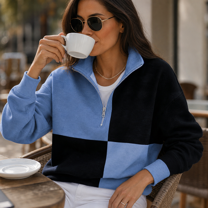 Woman drinking coffee in a blue and black colorblock sweatshirt