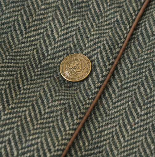 Antique brass button and brown piping on green herringbone tweed