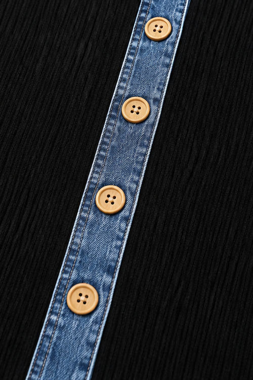 Close up of the denim placket and wooden buttons on a black knit jacket