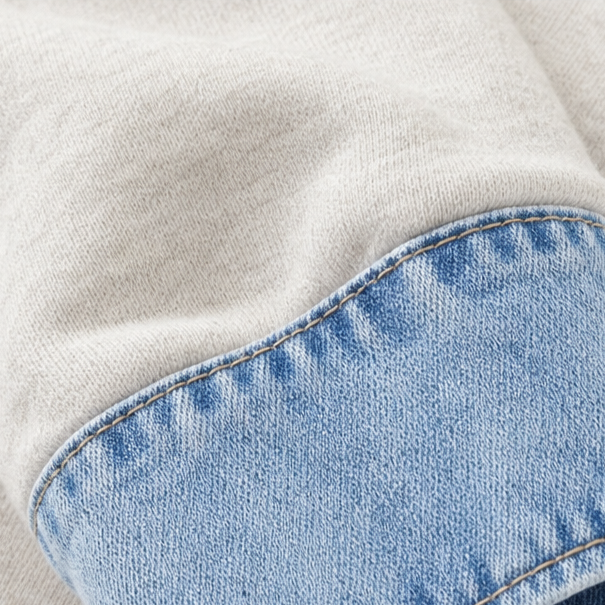 Denim cuff stitched to the cream sleeve of a sweatshirt