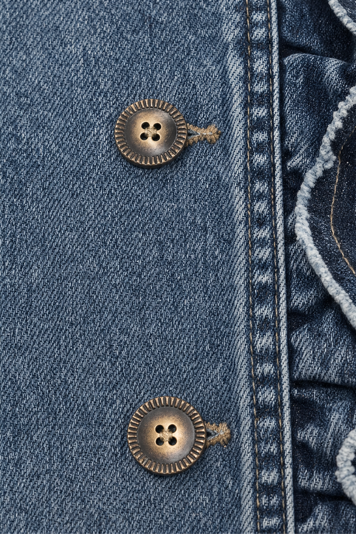 Two antique buttons on the ruffled front of a denim jacket