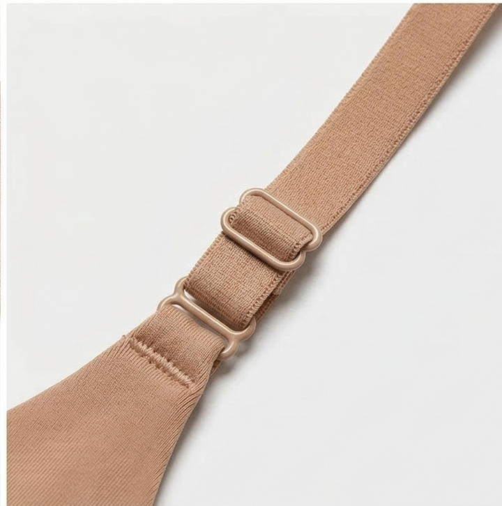 Nude bra strap with two sliders on a white surface