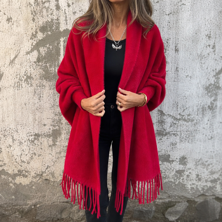 Red draped shawl collar fringed wrap worn over black jeans