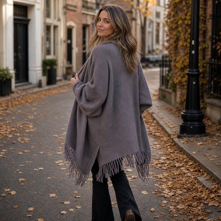 Back view of a grey fringed shawl wrap on an autumn street