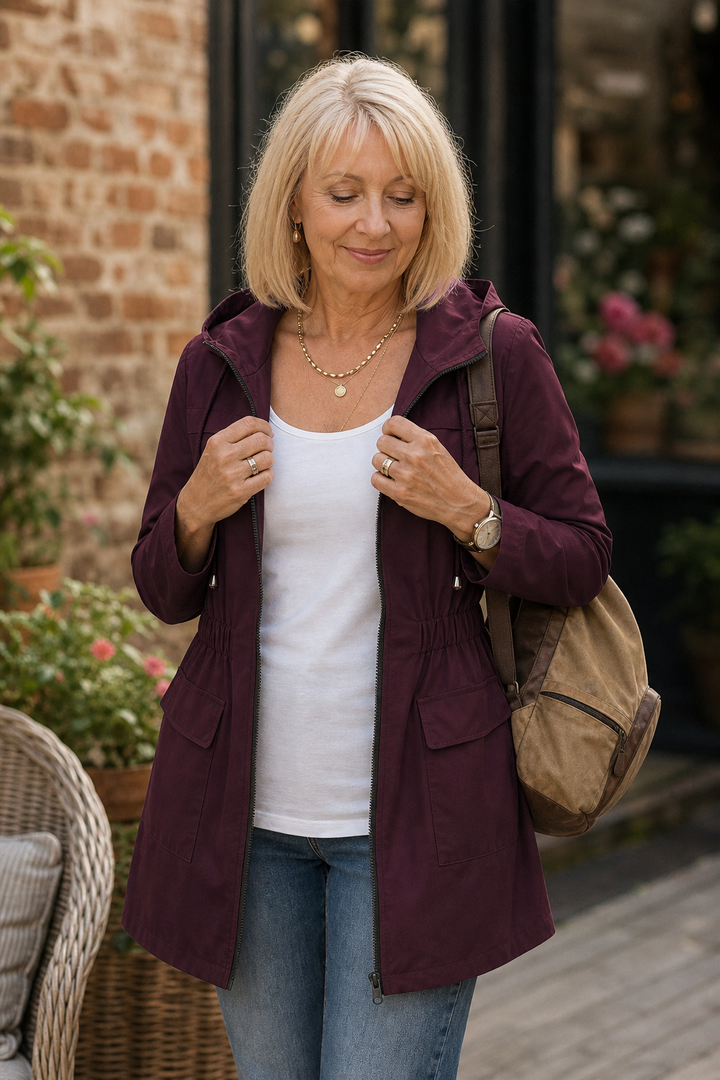 Burgundy hooded anorak worn with a tote bag beside roses