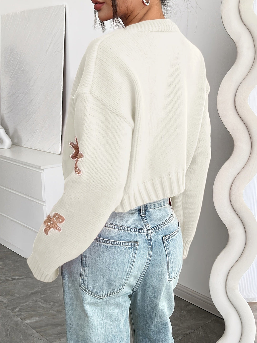 Back view of a cream cropped cardigan with gingerbread sleeve appliques