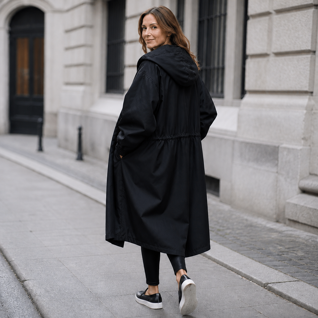 Side view of a black hooded longline coat on a city street