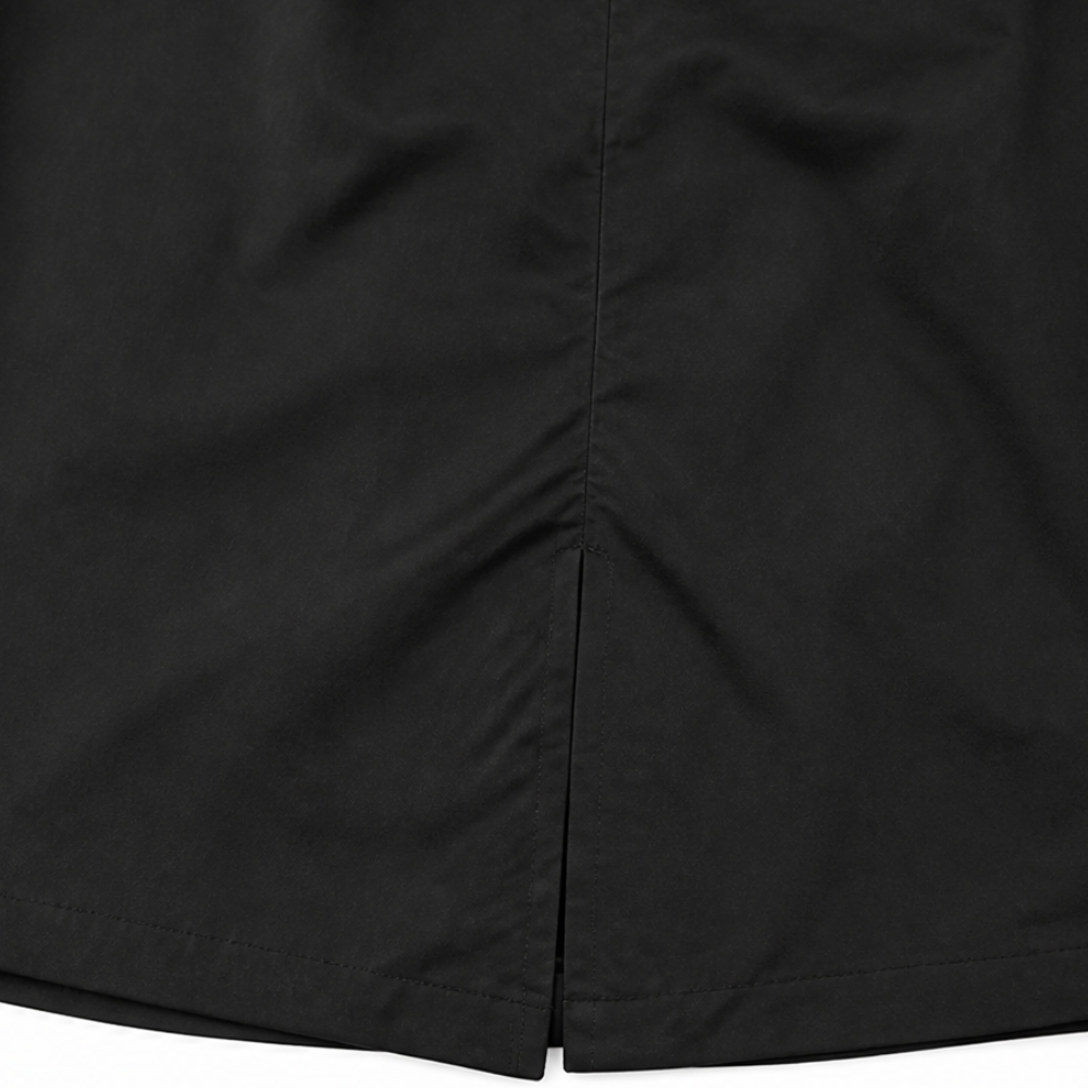 Side vent at the hem of a black longline coat