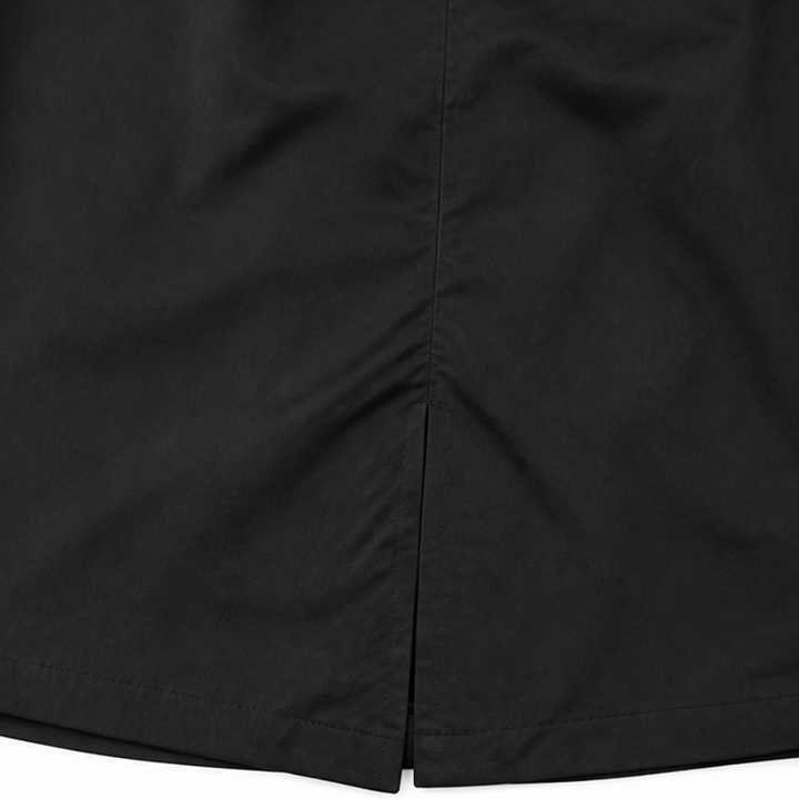 Side vent at the hem of a black longline coat
