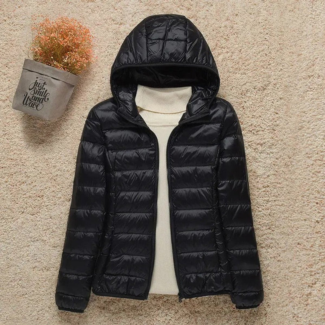 Black hooded packable puffer jacket laid flat