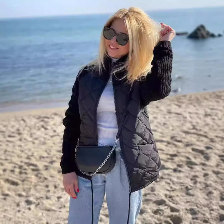 Black quilted jacket with knit sleeves worn on a beach