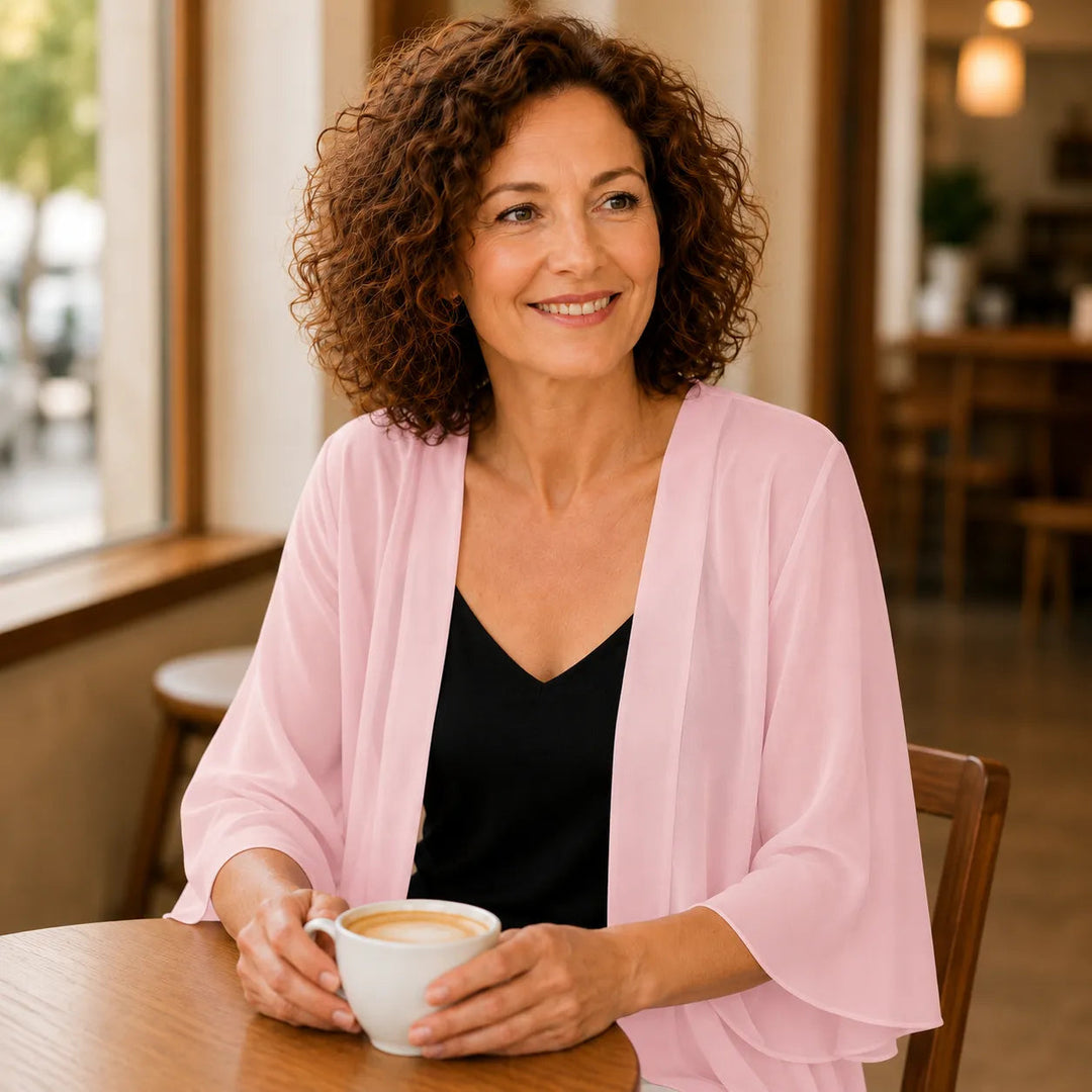 Woman with a coffee at a cafe in a pink chiffon cardigan