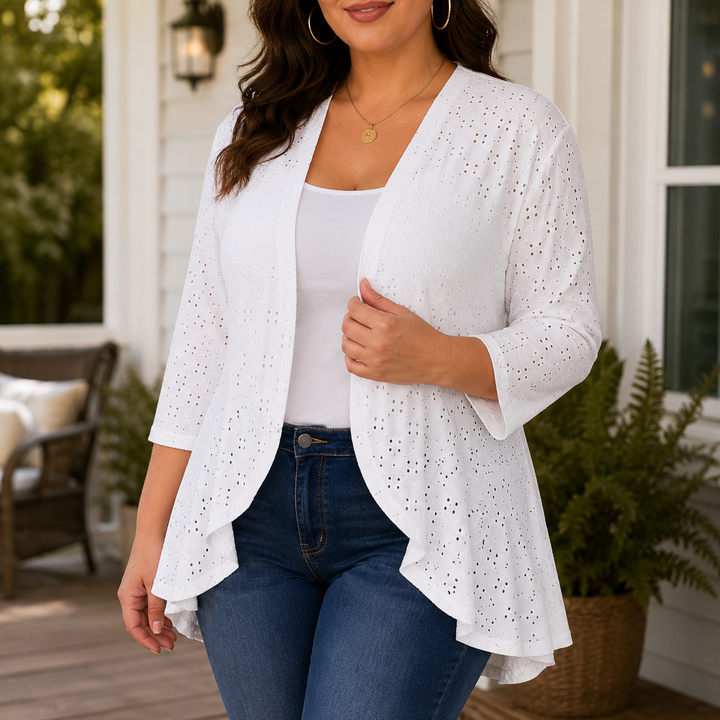 White eyelet open front cardigan worn on a porch with jeans