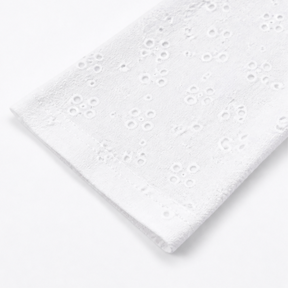 Folded sleeve of a white eyelet open front cardigan
