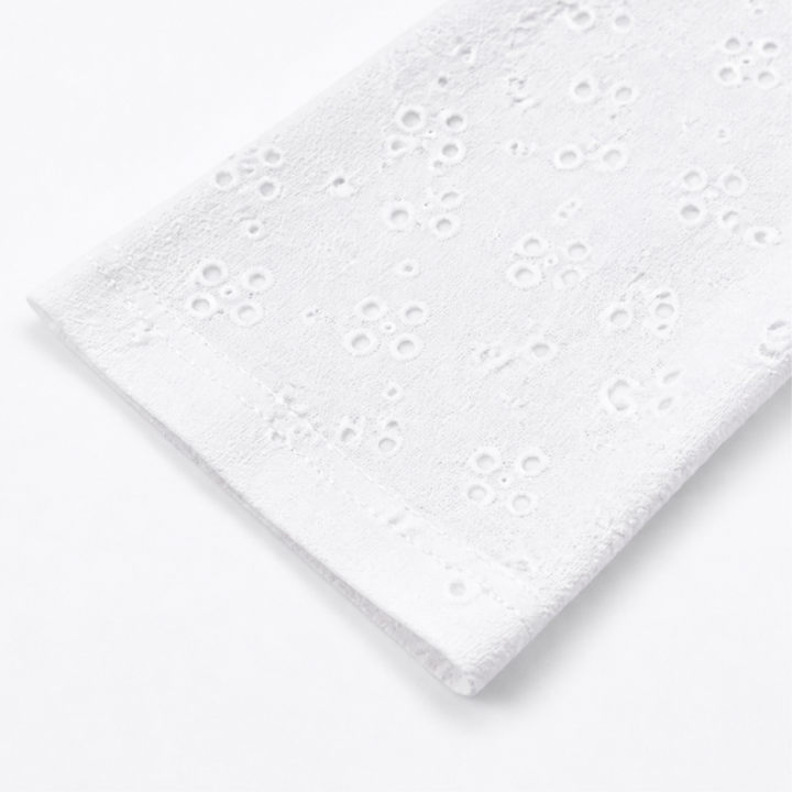 Folded sleeve of a white eyelet open front cardigan