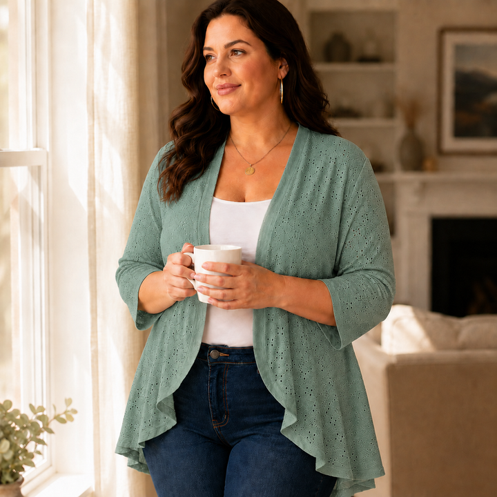 Woman with a mug by a window in a sage eyelet cardigan