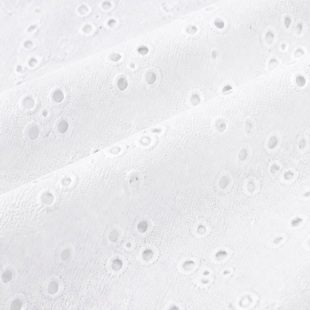 Close-up of the punched eyelet pattern on white fabric