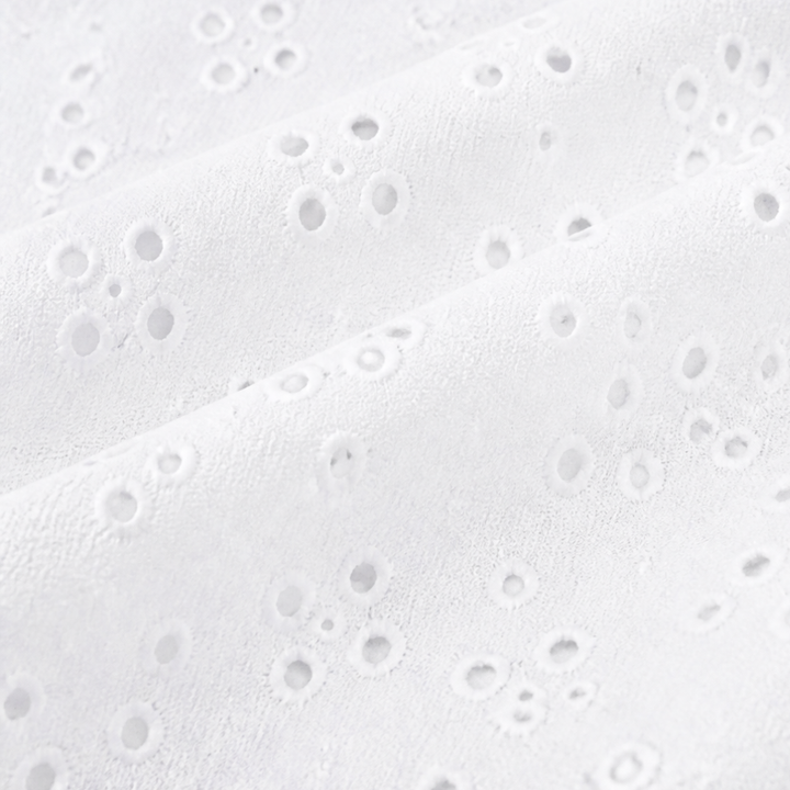 Close-up of the punched eyelet pattern on white fabric