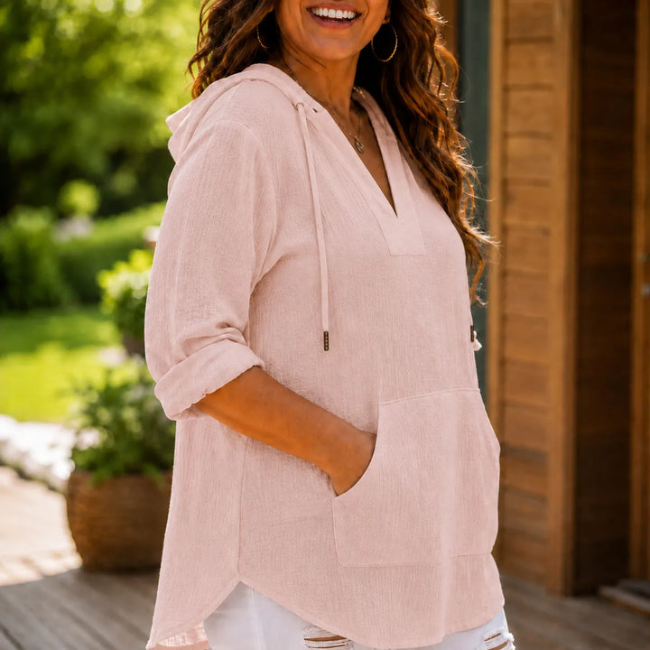Blush pink hooded top worn on a porch with a pocket detail