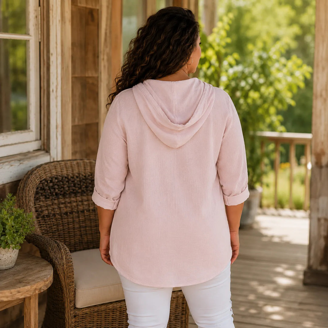 Back view of a blush pink lightweight hooded top on a porch