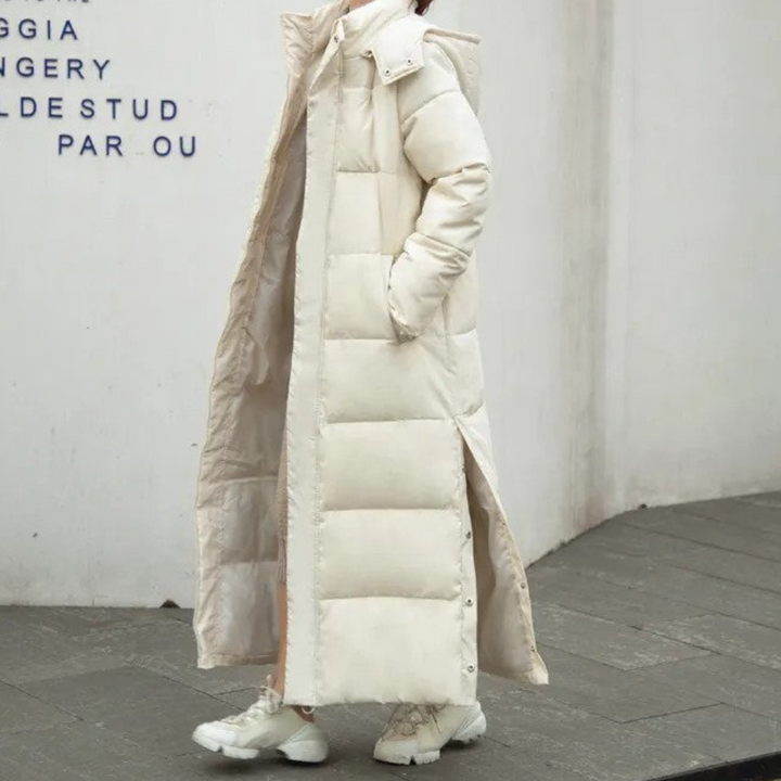 Cream long quilted coat with a stand collar against a white wall