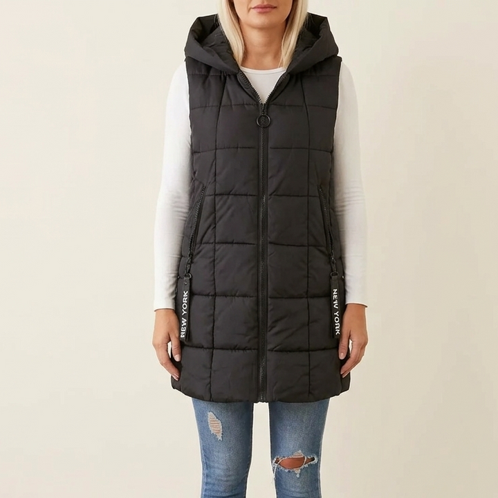 Black quilted hooded puffer vest over a white long sleeve top