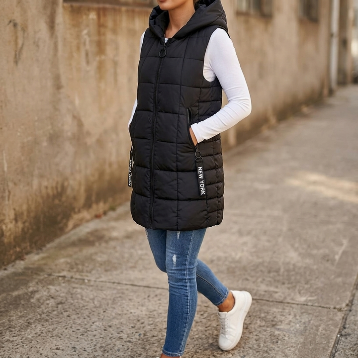 Black long quilted puffer vest worn with jeans on a stone lane