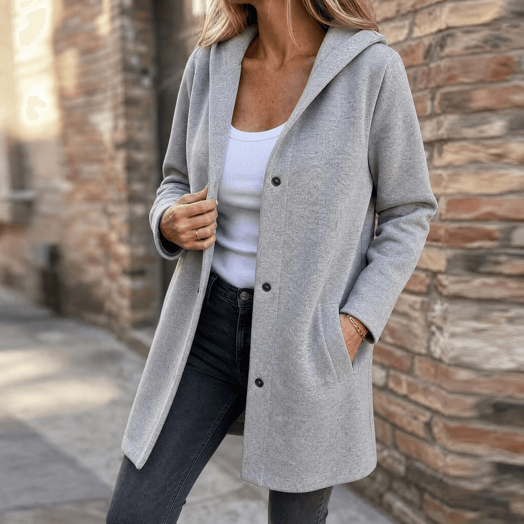 Woman wearing a light gray longline hooded button cardigan jacket with jeans
