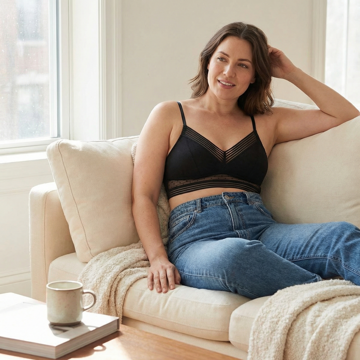 Woman on a sofa in a black lace bralette and jeans
