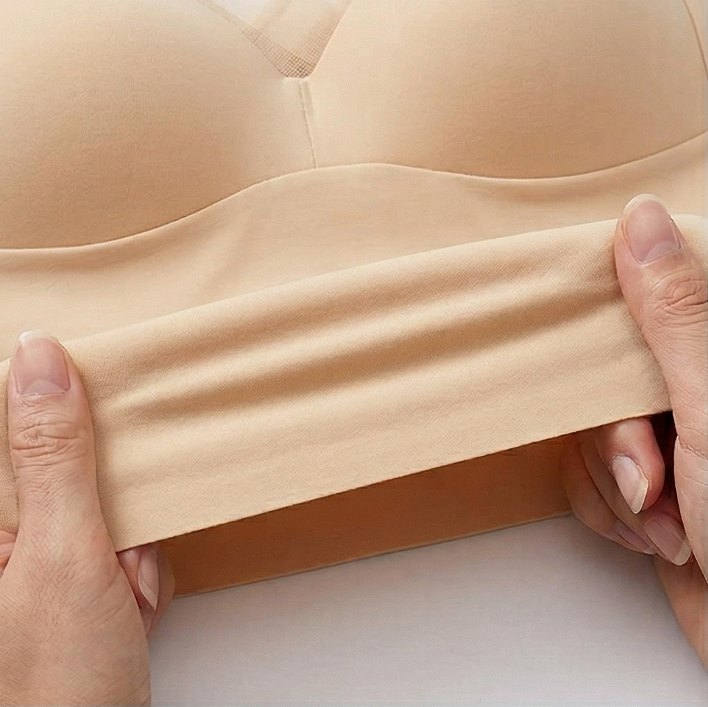 Hands stretching the nude bra flat to show the fabric give