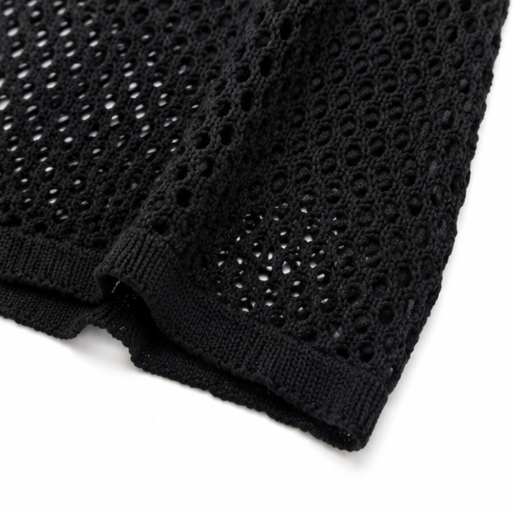 Close up of the black open knit fabric and ribbed hem of a cardigan