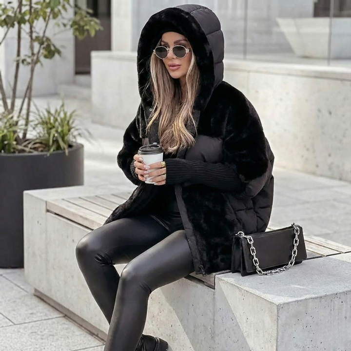 Woman seated in a black quilted hooded jacket with the hood up