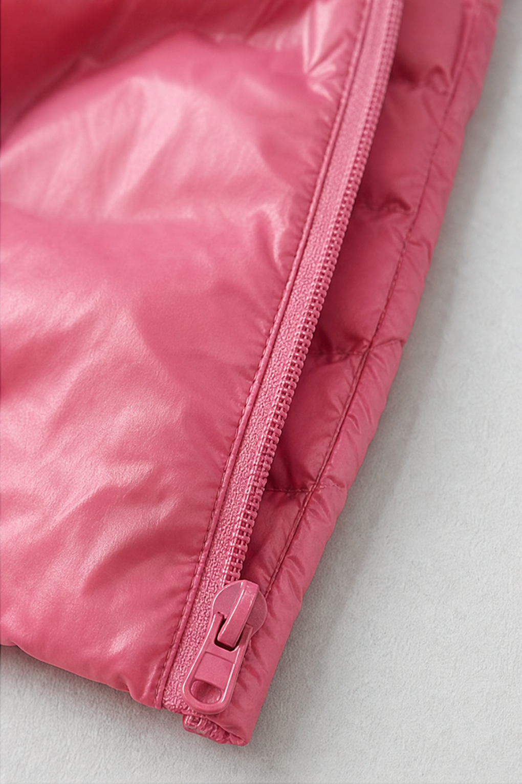 Close up of the zip and hem on a pink ultralight puffer coat