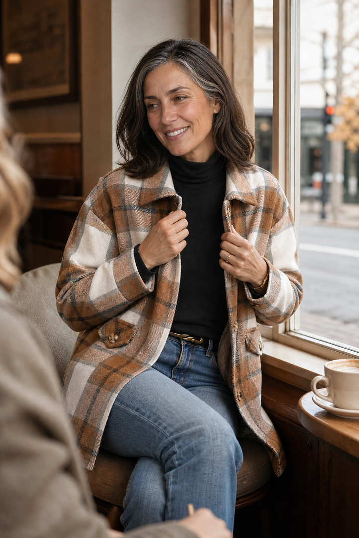 Woman at a cafe window in a camel plaid shirt jacket
