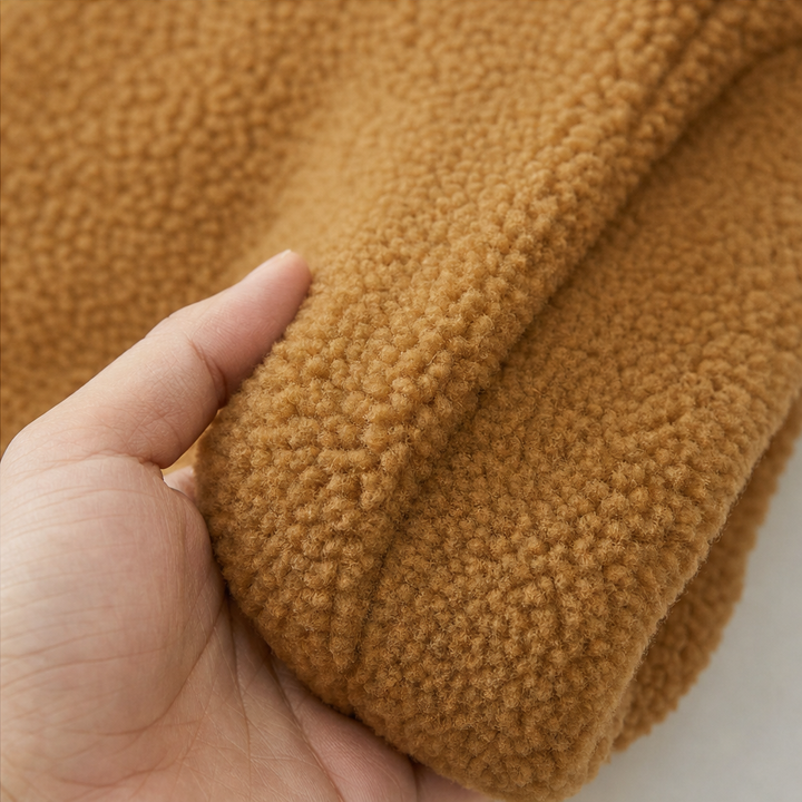 Hand holding the soft cuff of a caramel plush fleece jacket